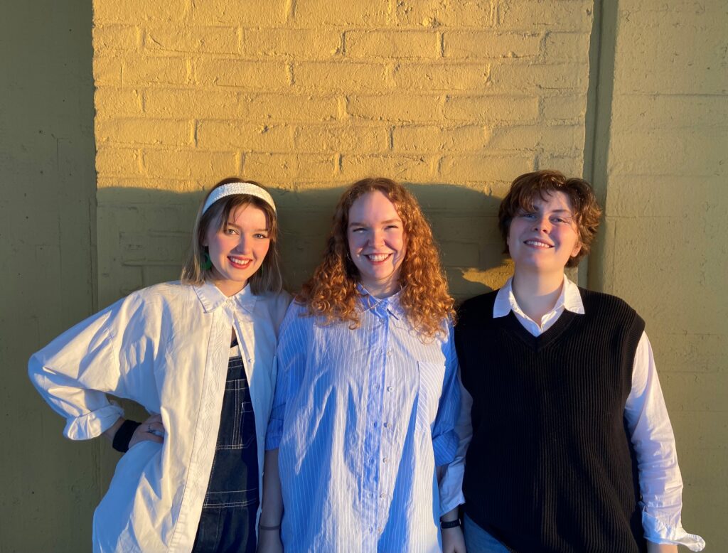 Tre tjejer som står i solen